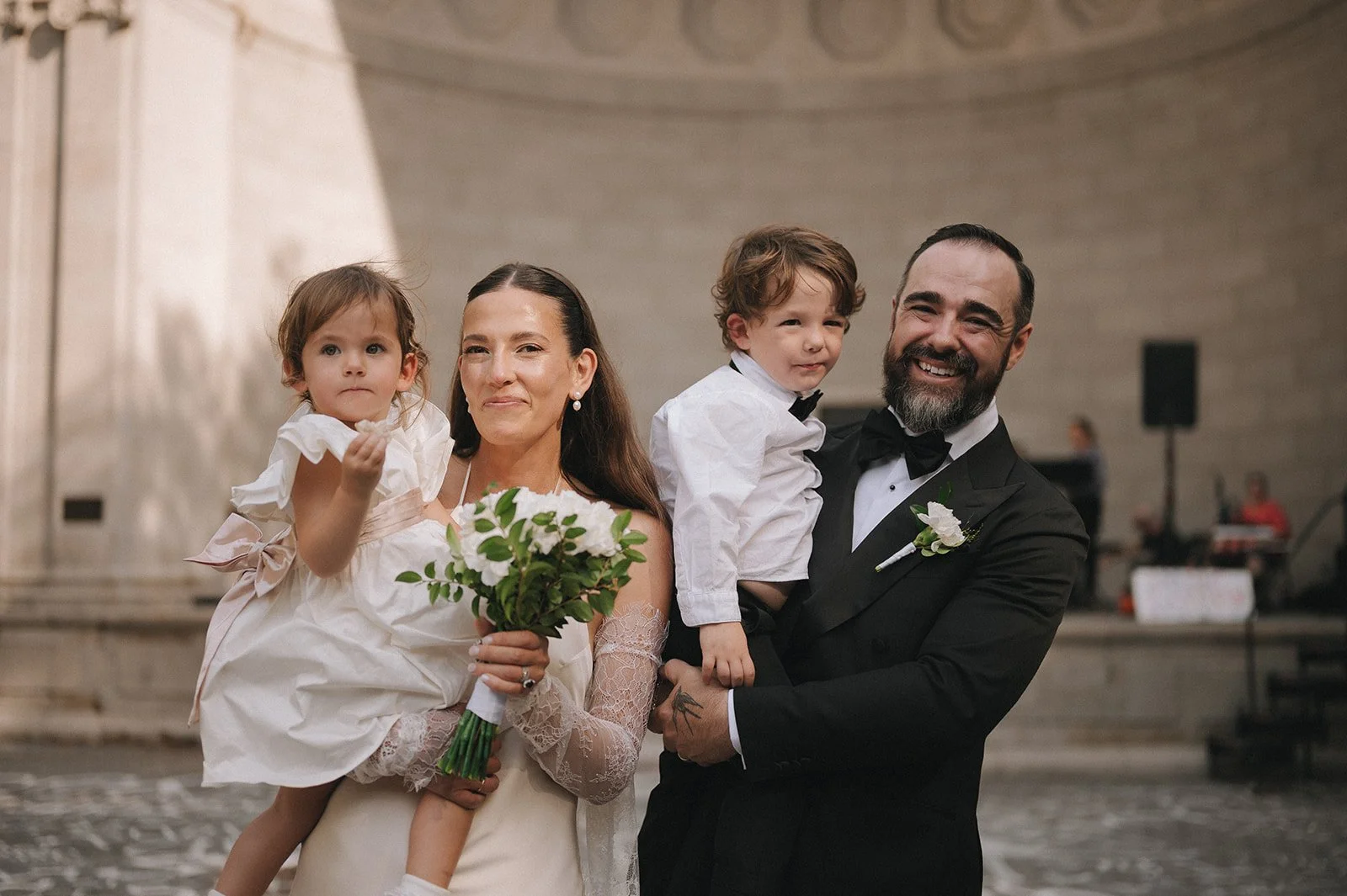 Bride and groom holding their two children at Naumburg Banshell after their Cakewalk micro wedding.