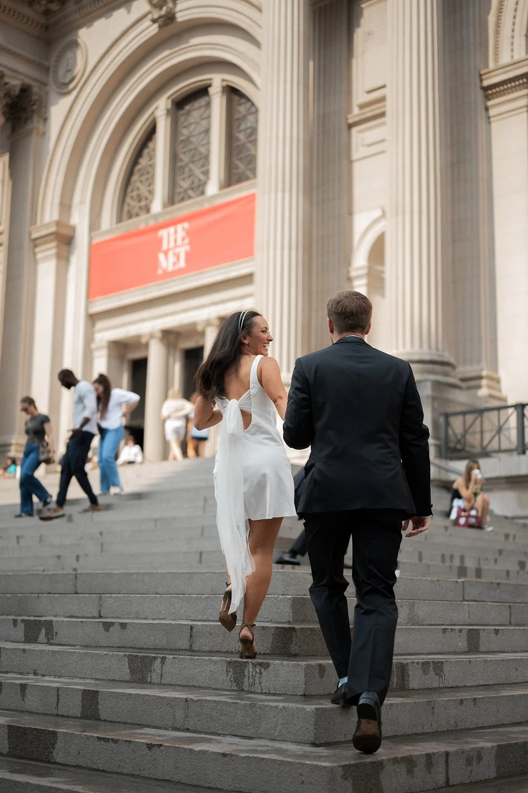 Newlyweds walking up The Met’s grand staircase after their NYC elopement ceremony.
