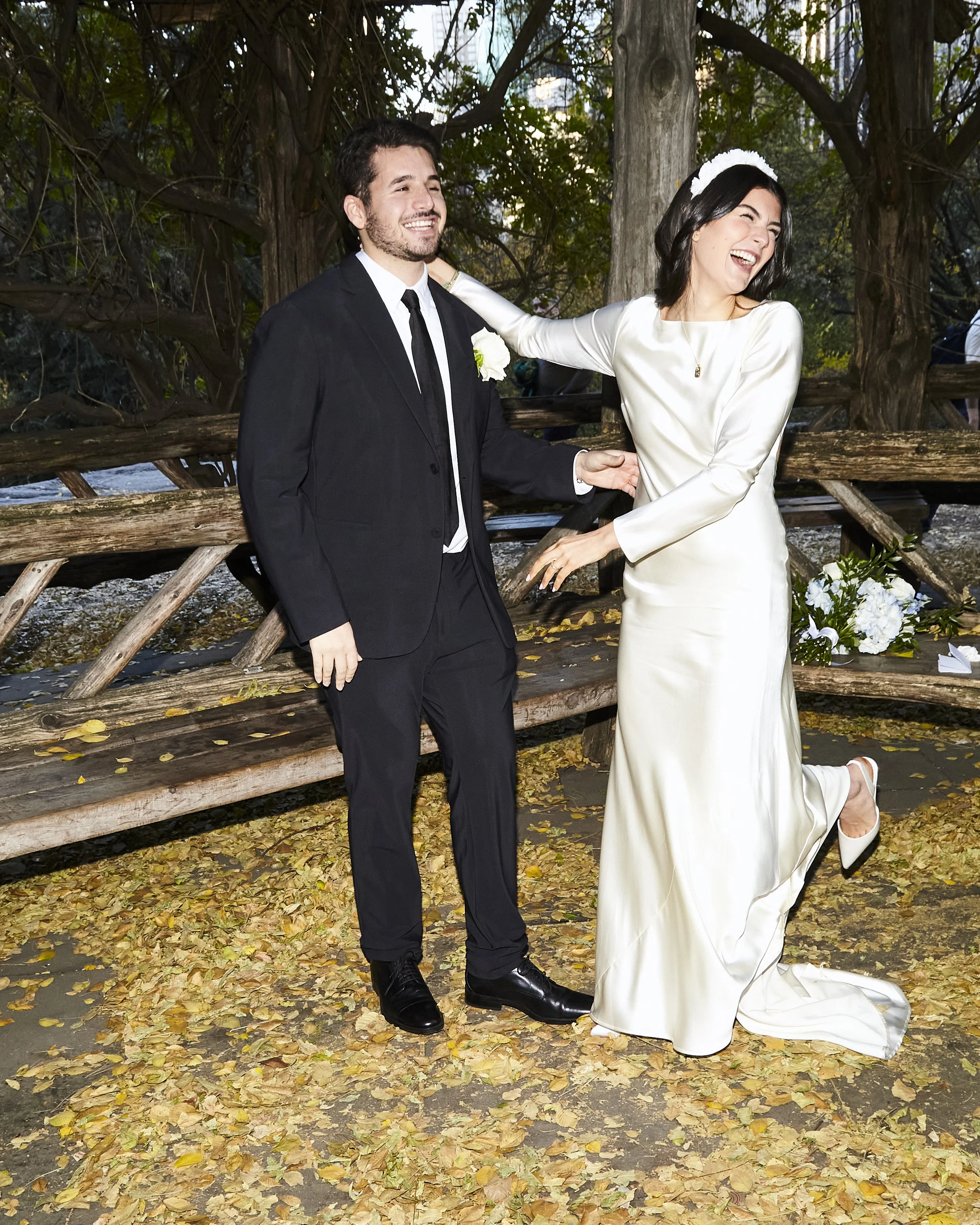 Bride and groom laughing during their Cop Cot elopement ceremony at Central Park, with fall foliage around them.