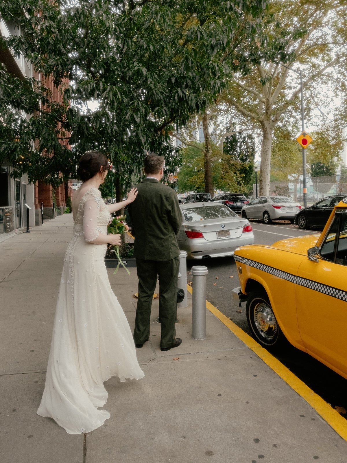 Bride touching groom on the shoulder for a first look, next to a yellow NYC taxi cab before their Cakewalk elopement ceremony.