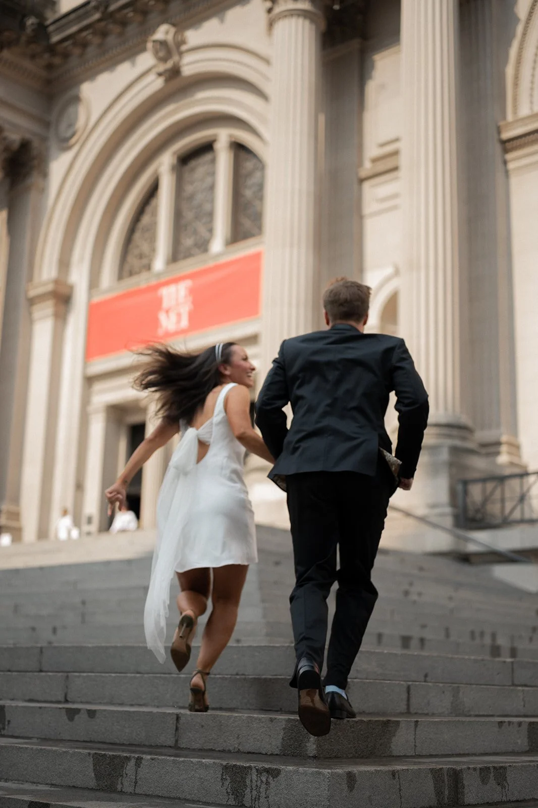 Kayla and Zach running up the grand front steps of the Metropolitan Museum of Art after their ceremony.