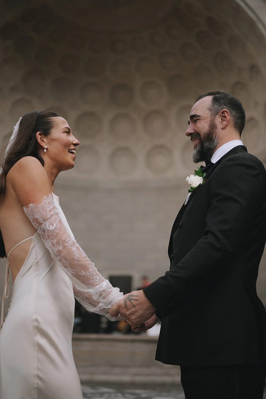Bride and groom holding hands in front of Naumburg Bandshell behind them at their Central Park micro wedding by Cakewalk.