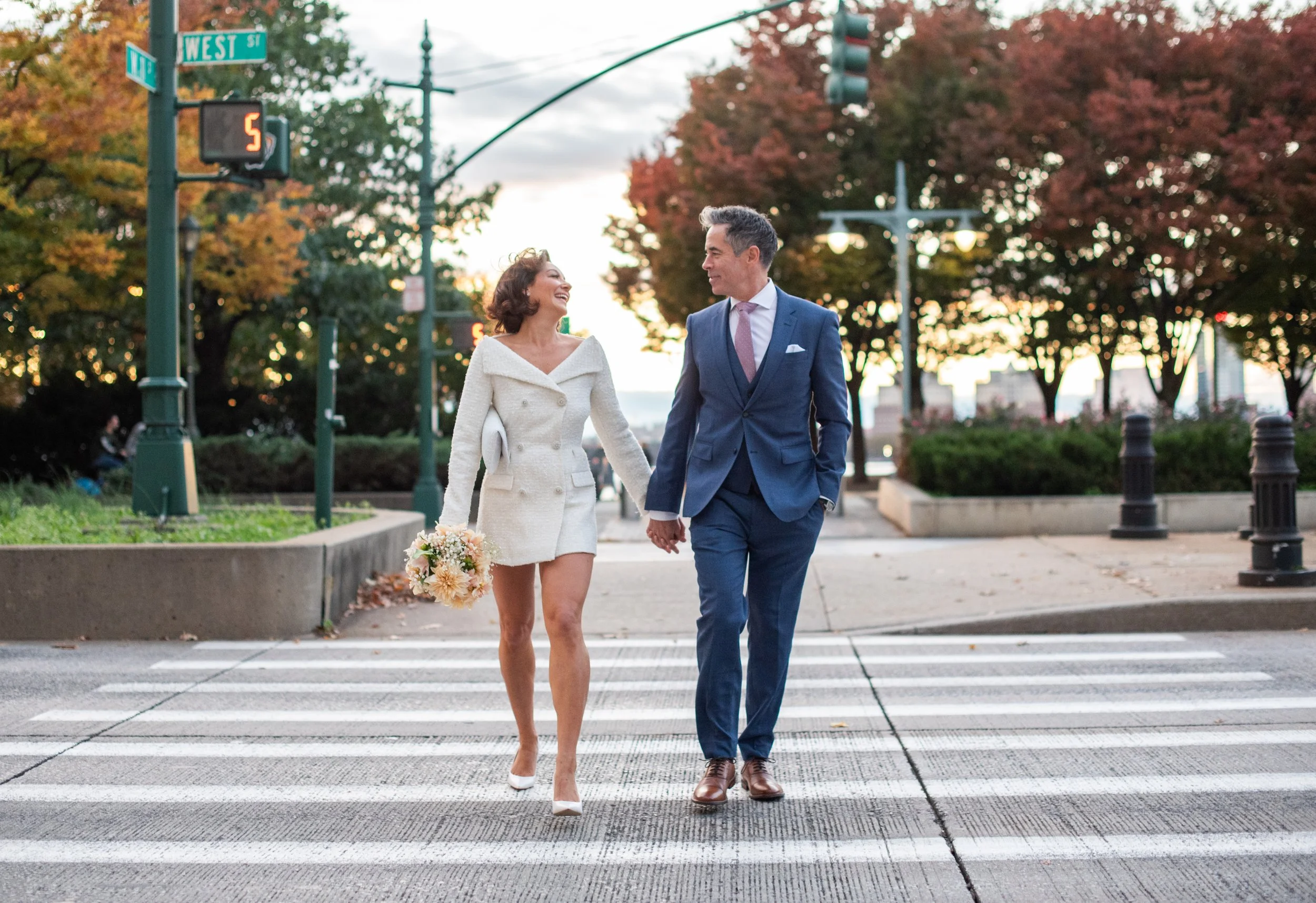 Bride and groom crossing the street and looking at each other leaving Hudson River Park after their Cakewalk elopement ceremony.