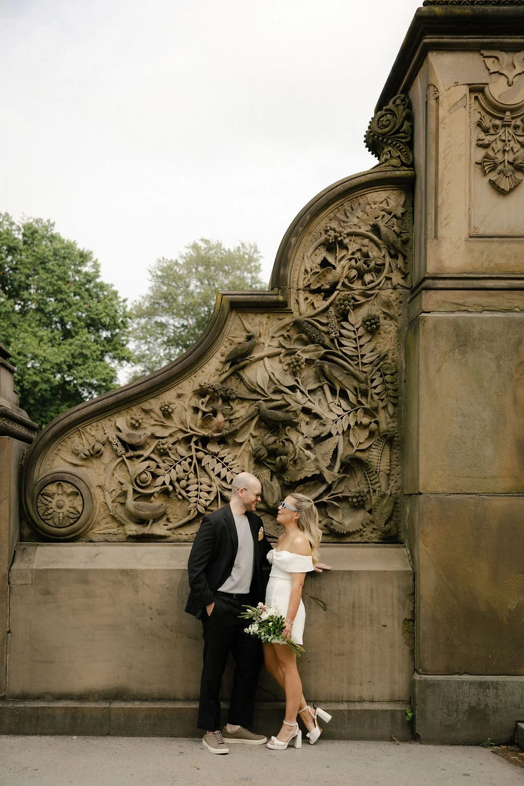 Bride and groom posing in front of sculptures at Bethesda Terrace in Central Park, on the way to their Cakewalk elopement.