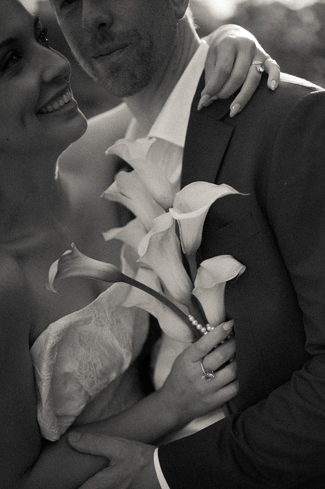 Bride and groom holding each other and flowers at their Bow Bridge, Central Park elopement ceremony.