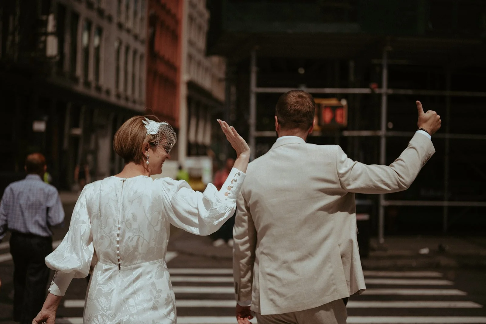 Just-married couple walking together through a New York City crosswalk after their elopement ceremony.