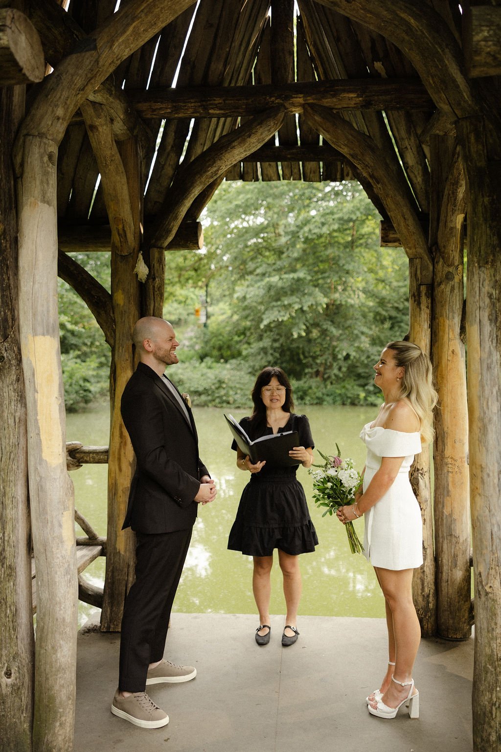 Wagner Cove wedding ceremony at Central Park, with Chloe and Sam under the wooden lakeside pavilion during their Cakewalk NYC elopement.