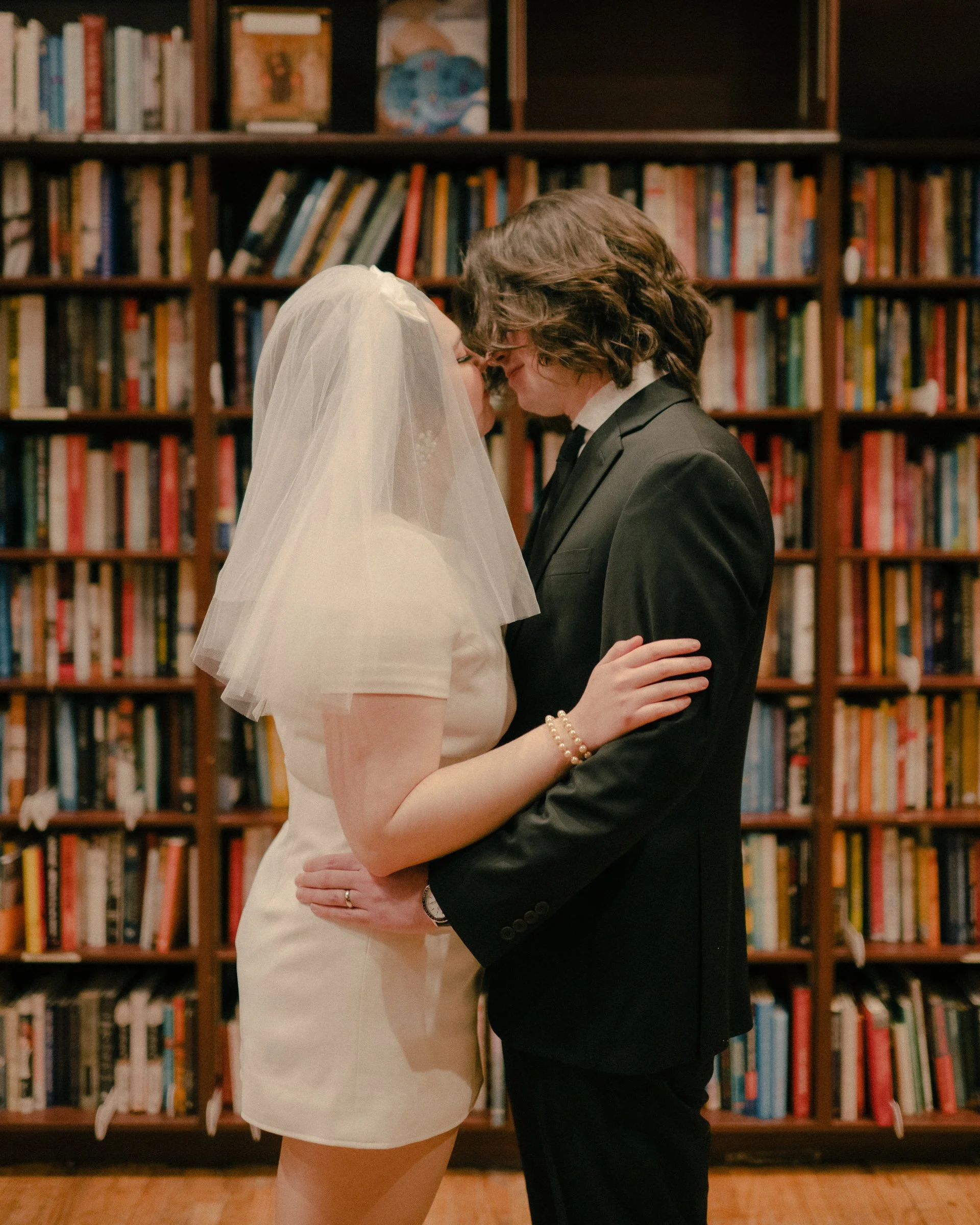 Couple sharing a quiet kiss surrounded by books during an intimate elopement at Housing Works Bookstore.