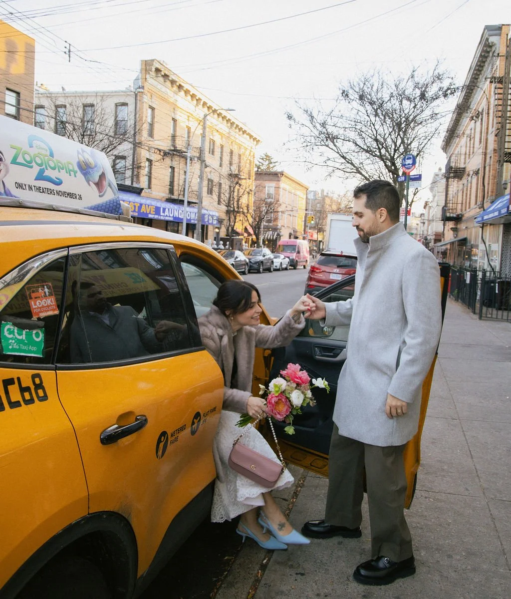 Newly married couple exiting a New York yellow taxi holding a bouquet after their Cakewalk elopement ceremony.