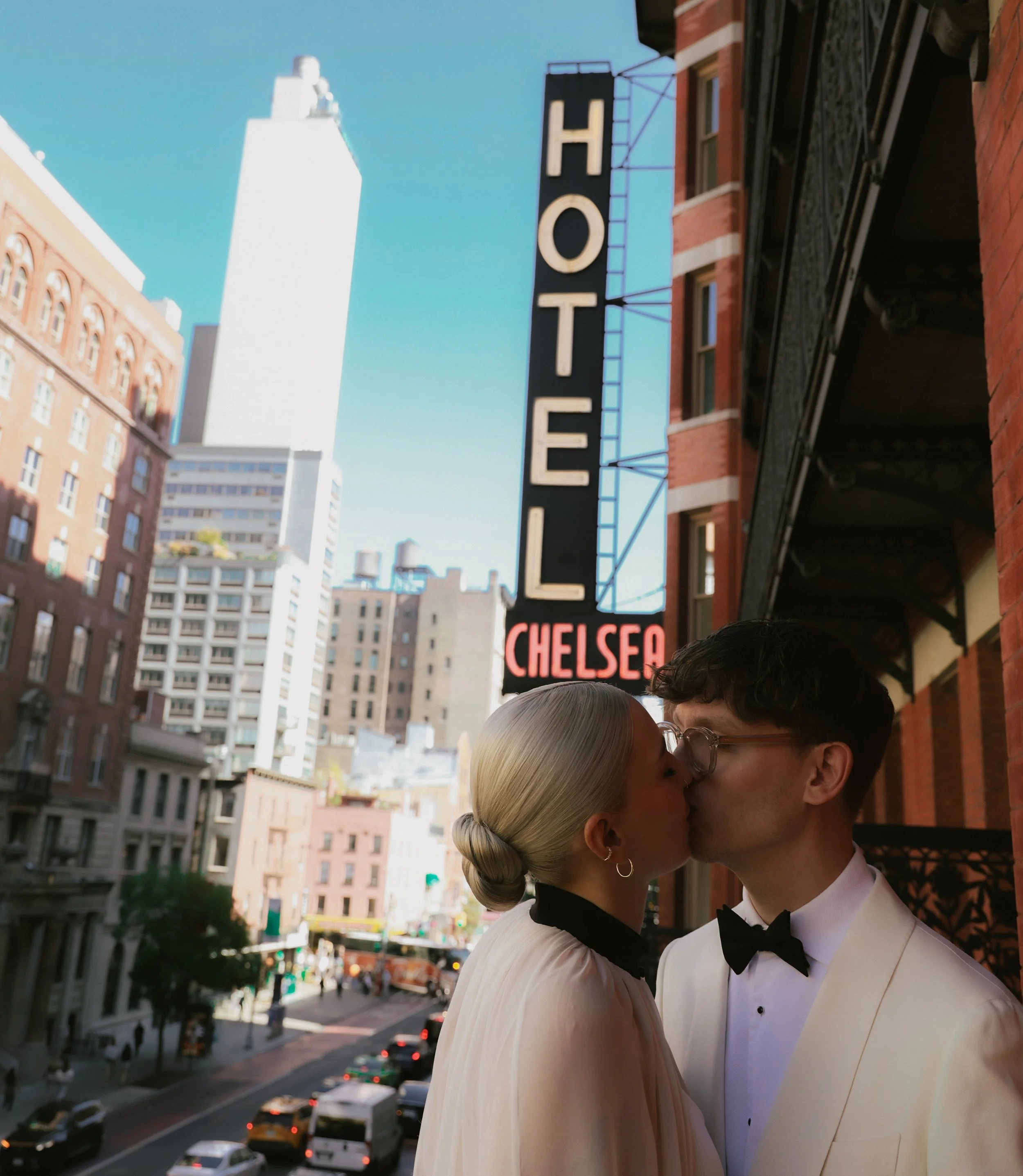 Bride and groom kiss on the balcony of their room at the Hotel Chelsea in Manhattan with the street and buildings in the background before their Cakewalk elopement.