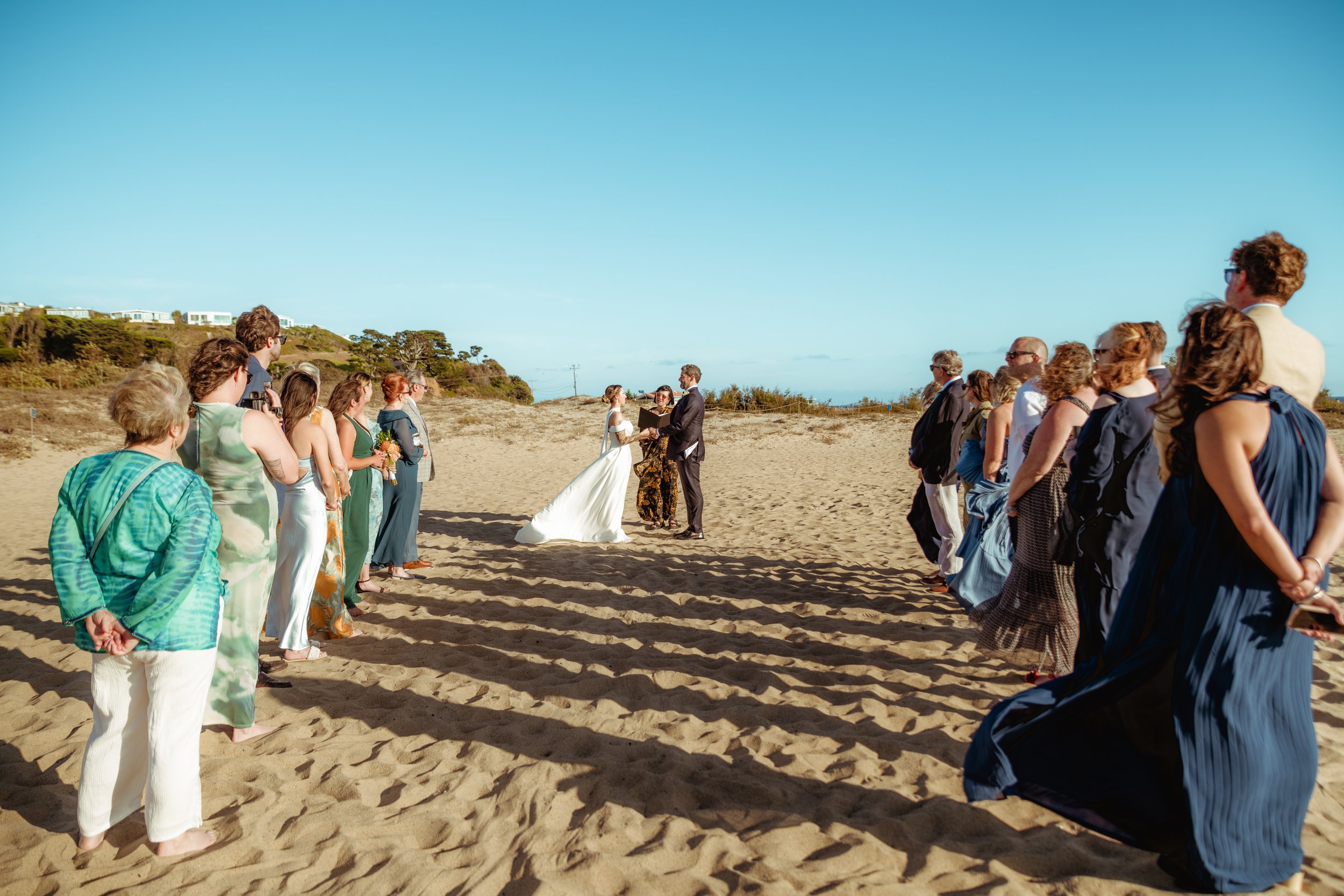 Bride and groom at the end of an aisle on the sand at Zuma Beach during their Cakewalk micro wedding.