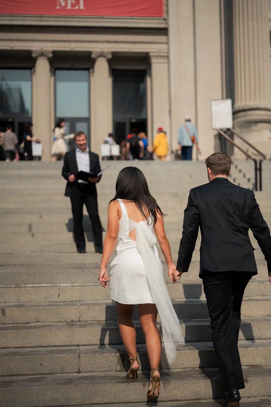 Bride and groom walking up the Met Museum steps towards their officiant for their Cakewalk elopement ceremony.