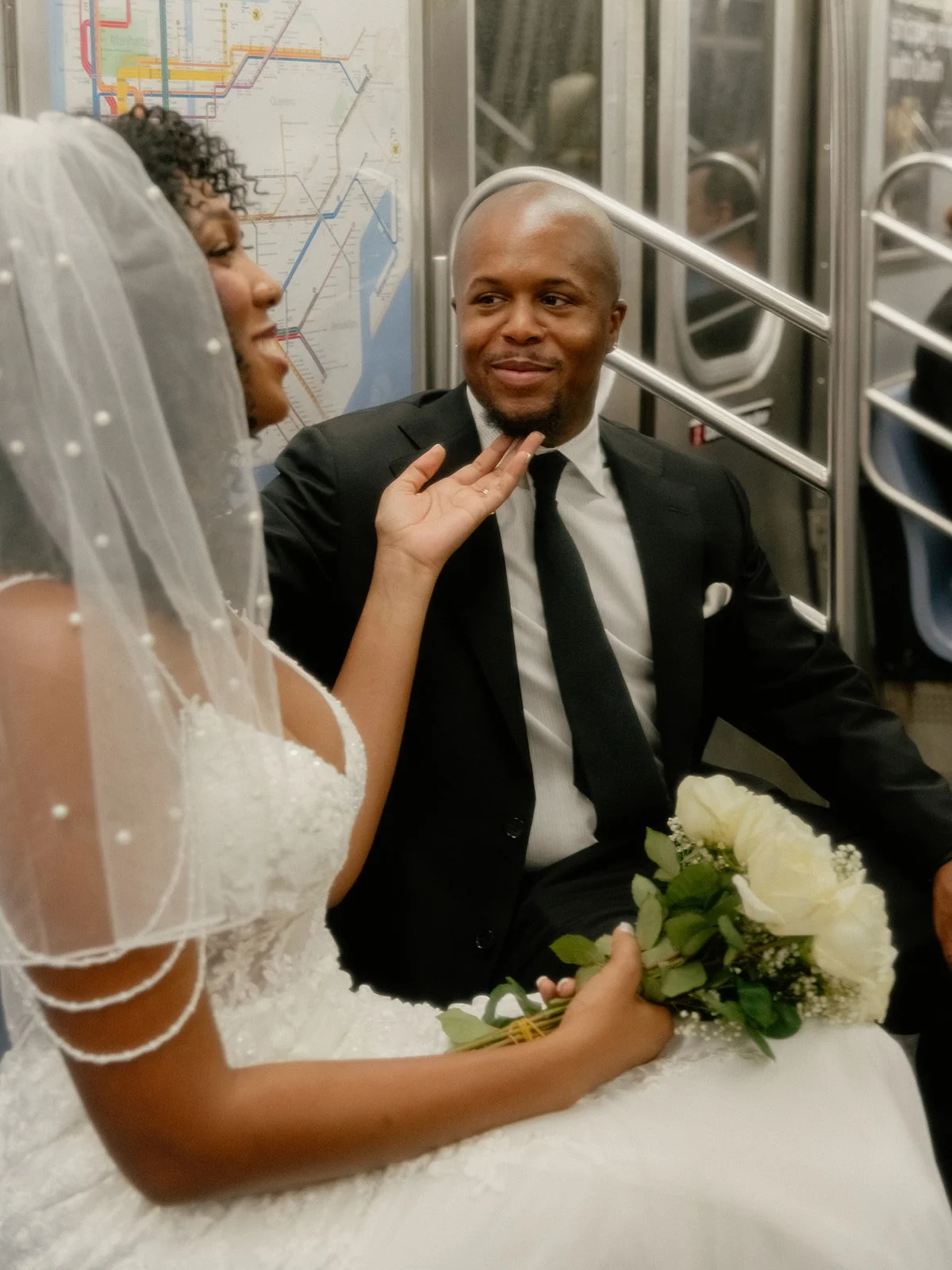 Bride and groom seated on the train, chatting in New York City after their Cakewalk elopement.