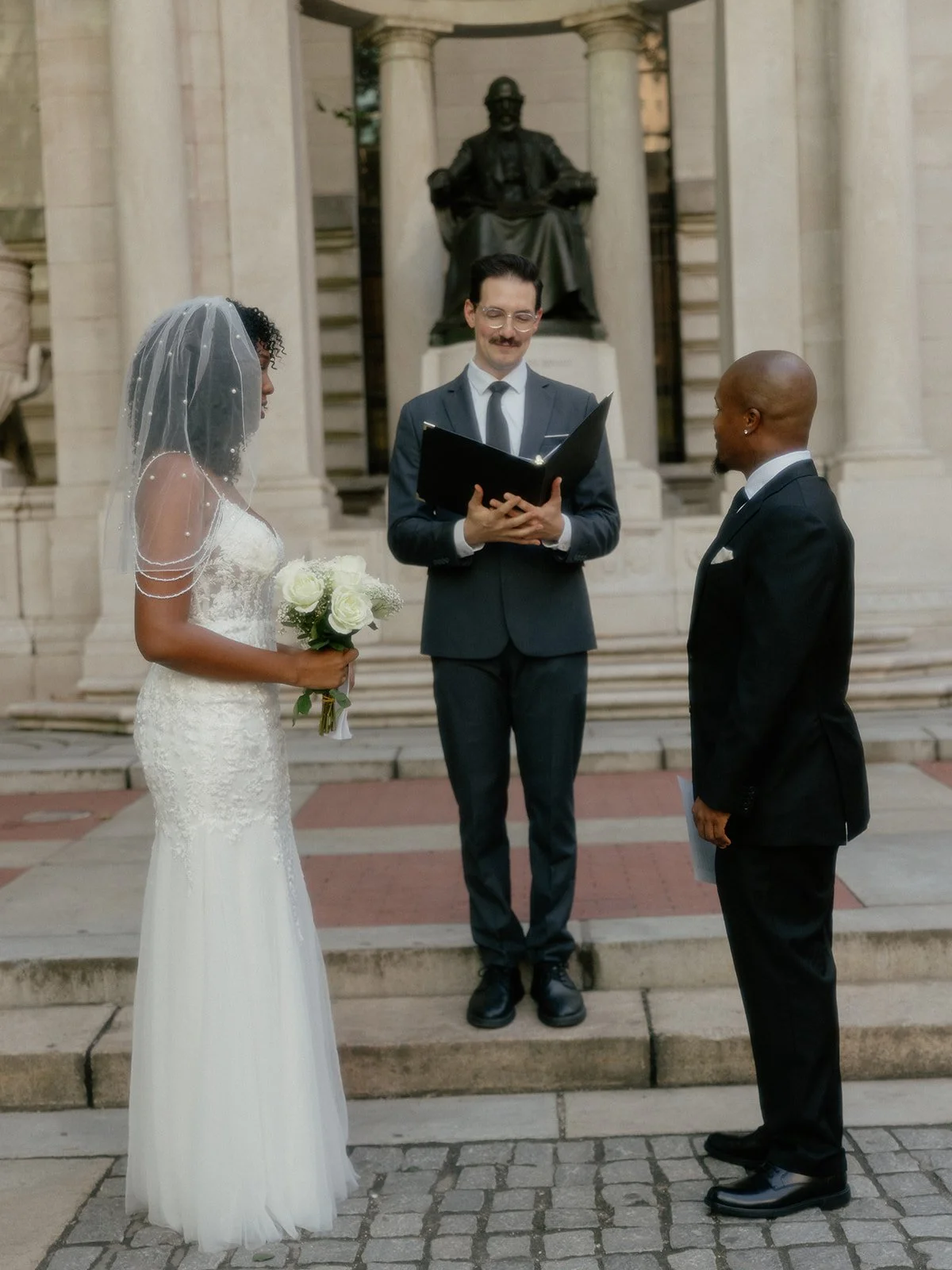 Bride and groom being married by their Cakewalk officiant in front of the statue at Bryant Park in NYC.