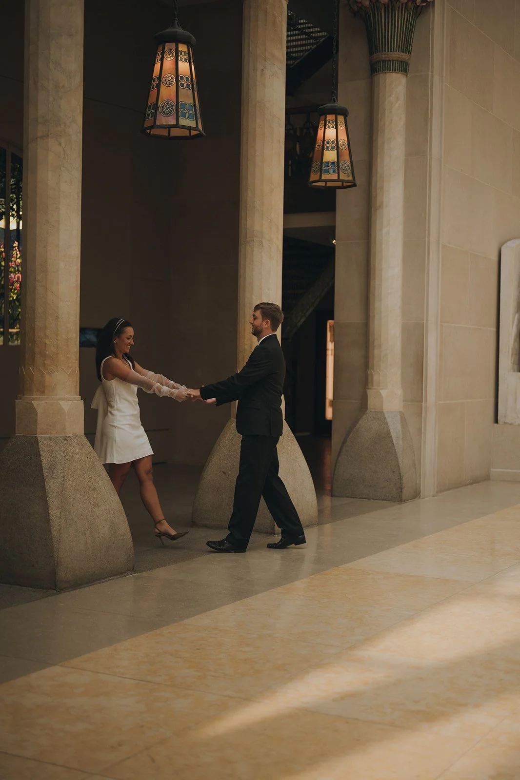 Bride and groom holding hands moving towards the colonnades at the Met Museum of Art.