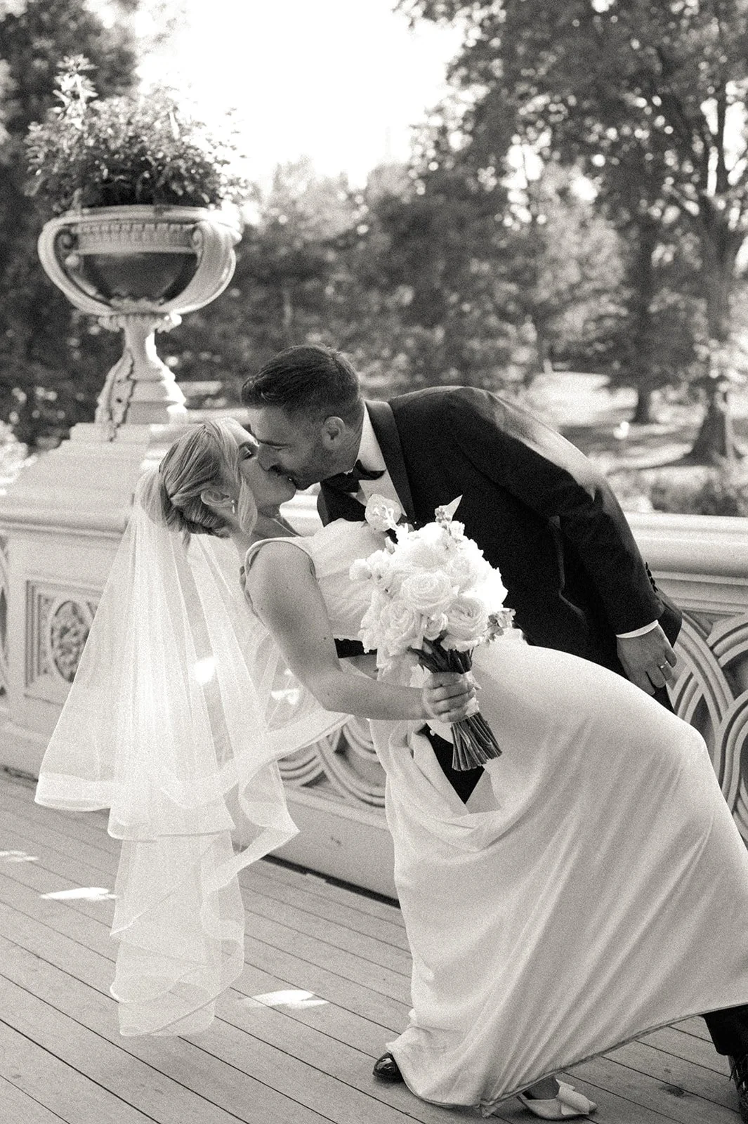 Bride and groom dipping and kissing on and Bow Bridge in Central Park after their Cakewalk micro wedding..