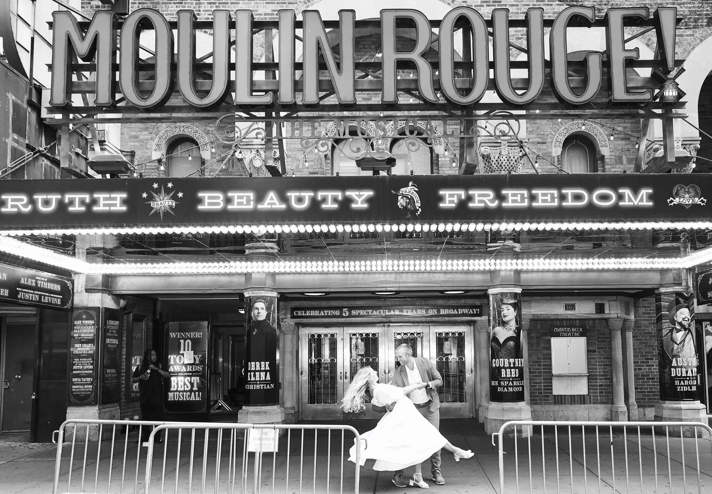 Bride and groom dancing in front of the Al Hirschfeld Theatre, where the marquee reads Moulin Rouge!