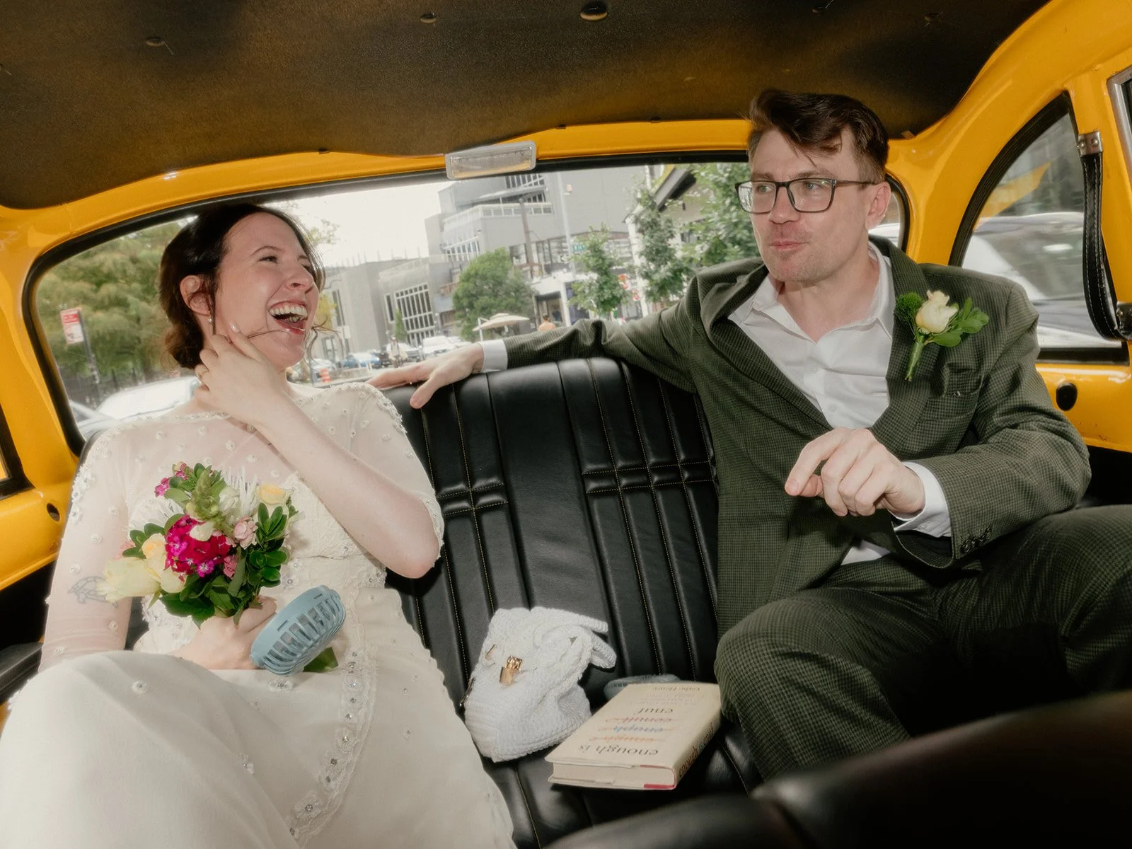 Bride and groom riding in the back seat of a vintage yellow taxi cab in New York, on the way to the High Line for their Cakewalk elopement ceremony.