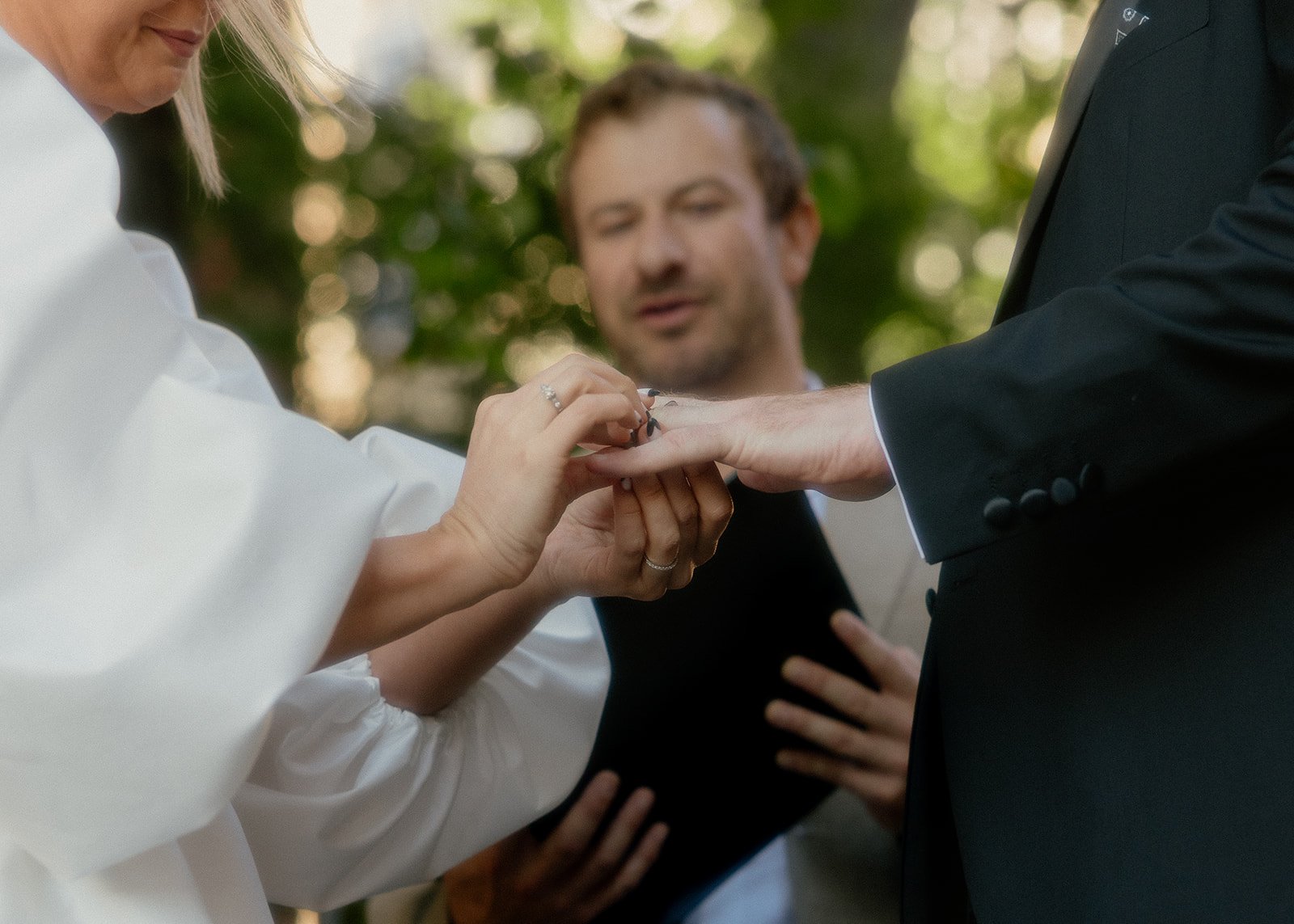 Bride and groom placing rings on each other's hands while officiant reads speech at Brooklyn elopement.