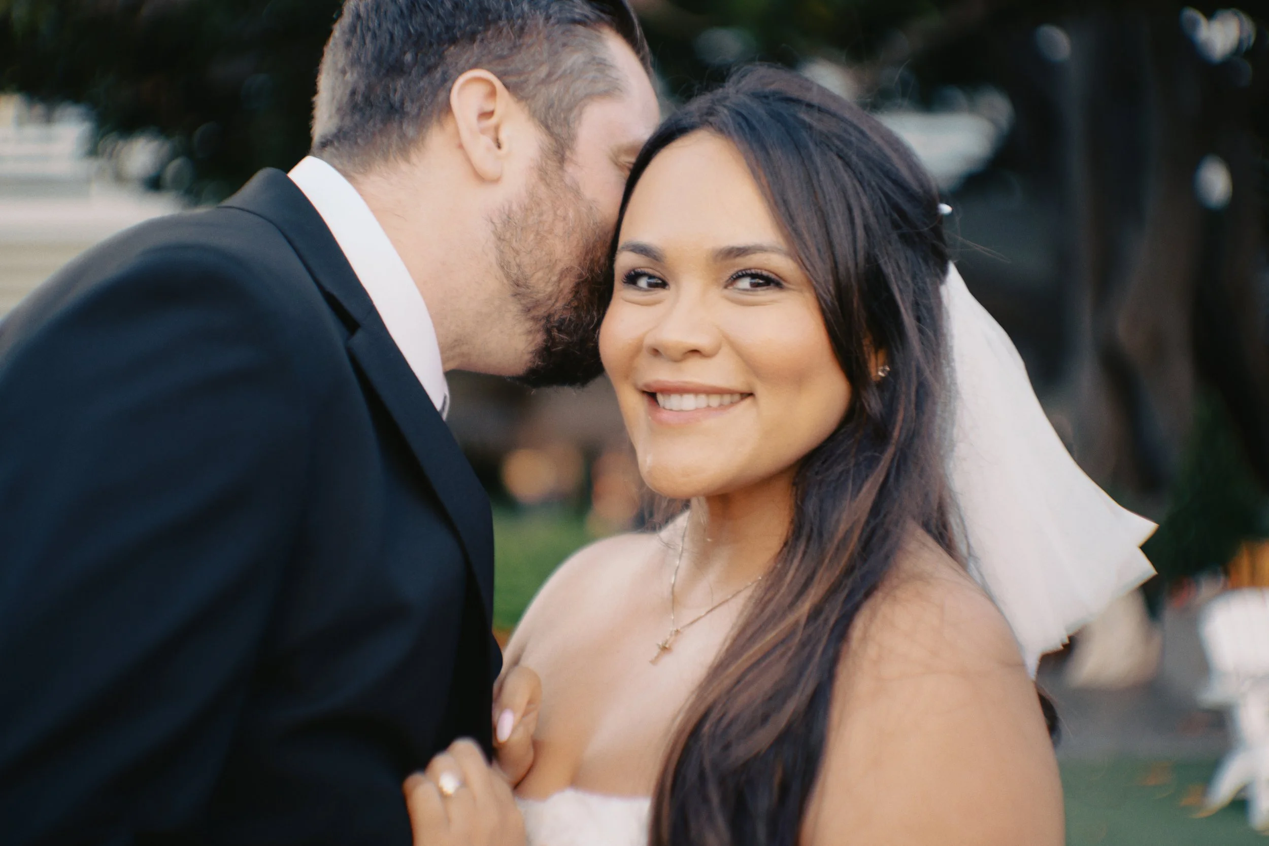Groom whispering into bride's ear at the Fairmont Miramar in Santa Monica before their Cakewalk elopement ceremony.