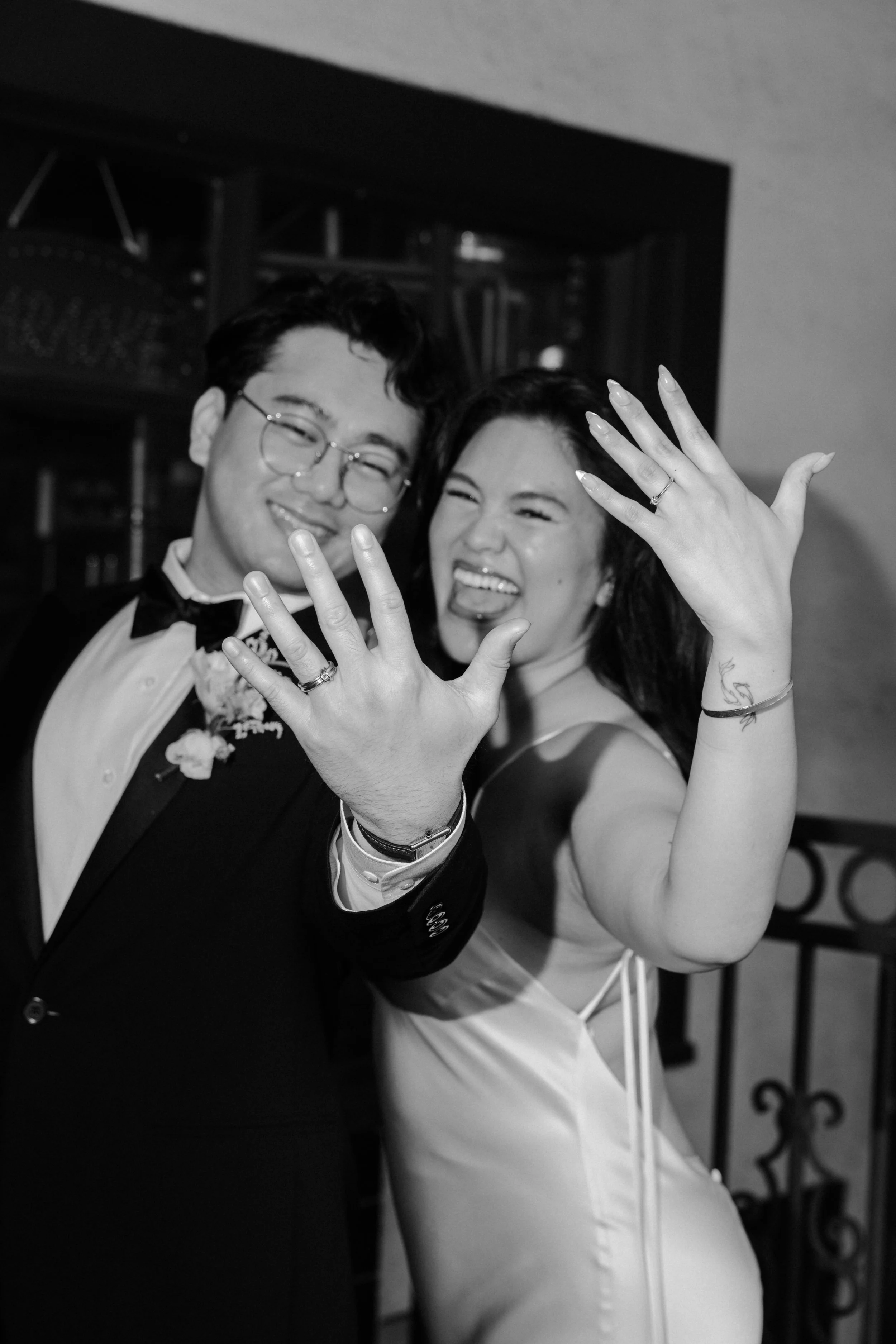 Bride and groom showing off their rings and smiling in front of a storefront in Old Pasadena after their Cakewalk elopement.