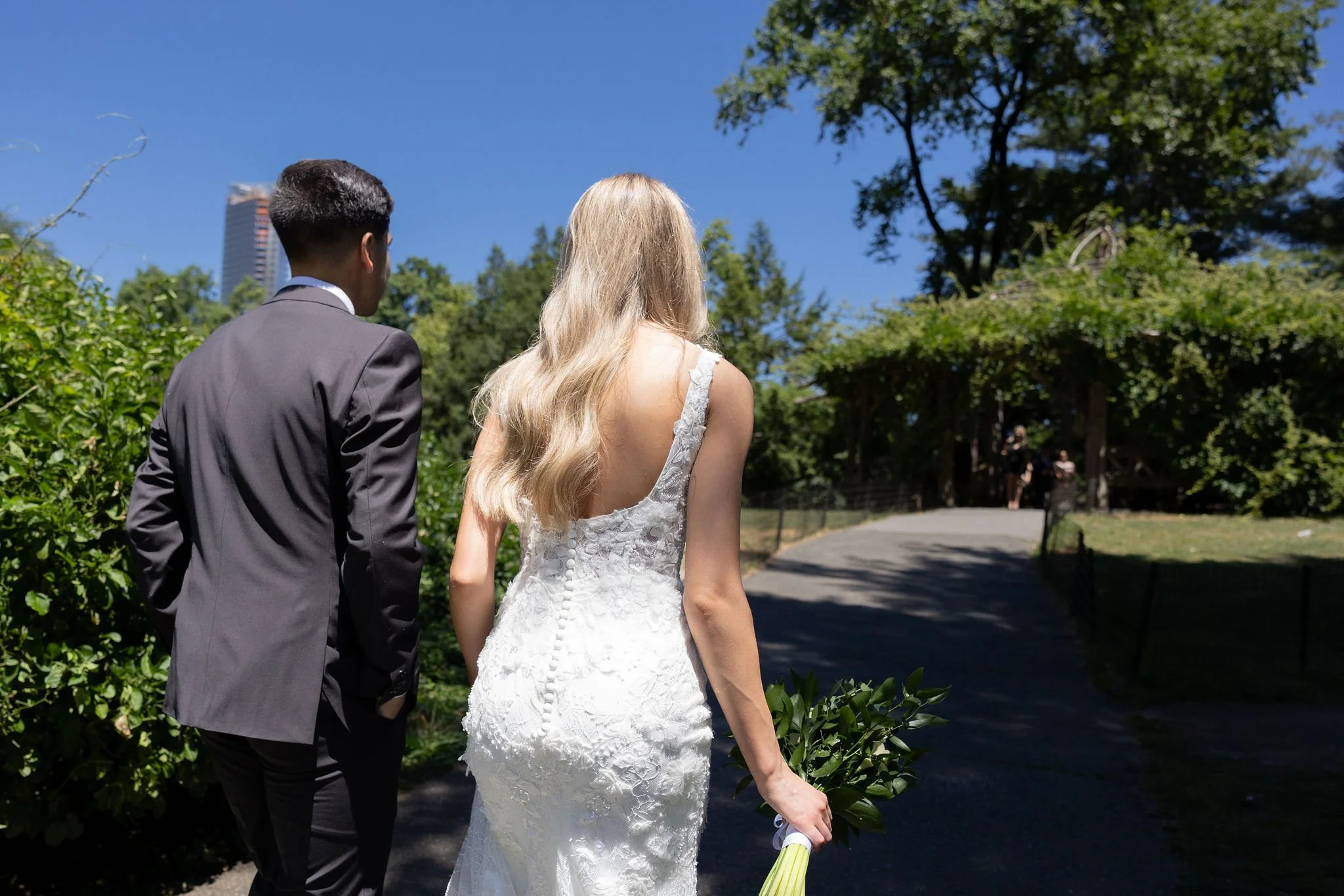 Bride and groom walking through the greenery in Central Park heading to Cop Cot  for their Cakewalk micro wedding.