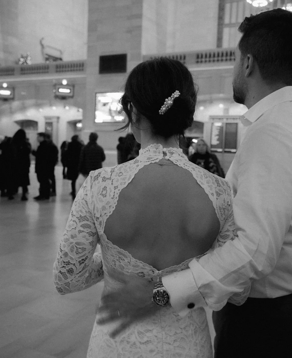 Black and white picture of married couple with a bouquet walking through Grand Central Station after their Cakewalk elopement ceremony.