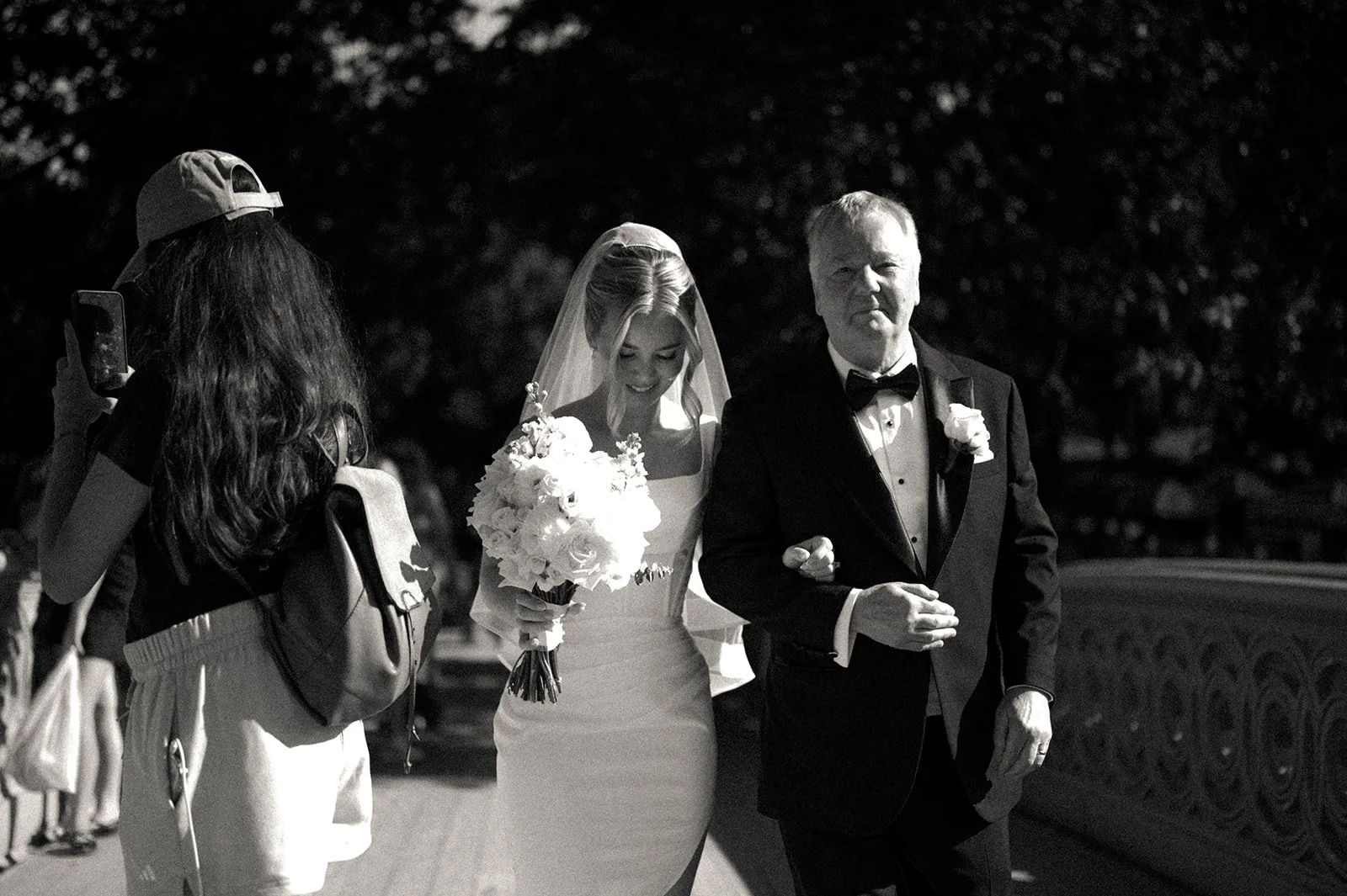 Bride holding flowers and being escorted by her father across Bow Bridge towards her micro wedding ceremony by Cakewalk.