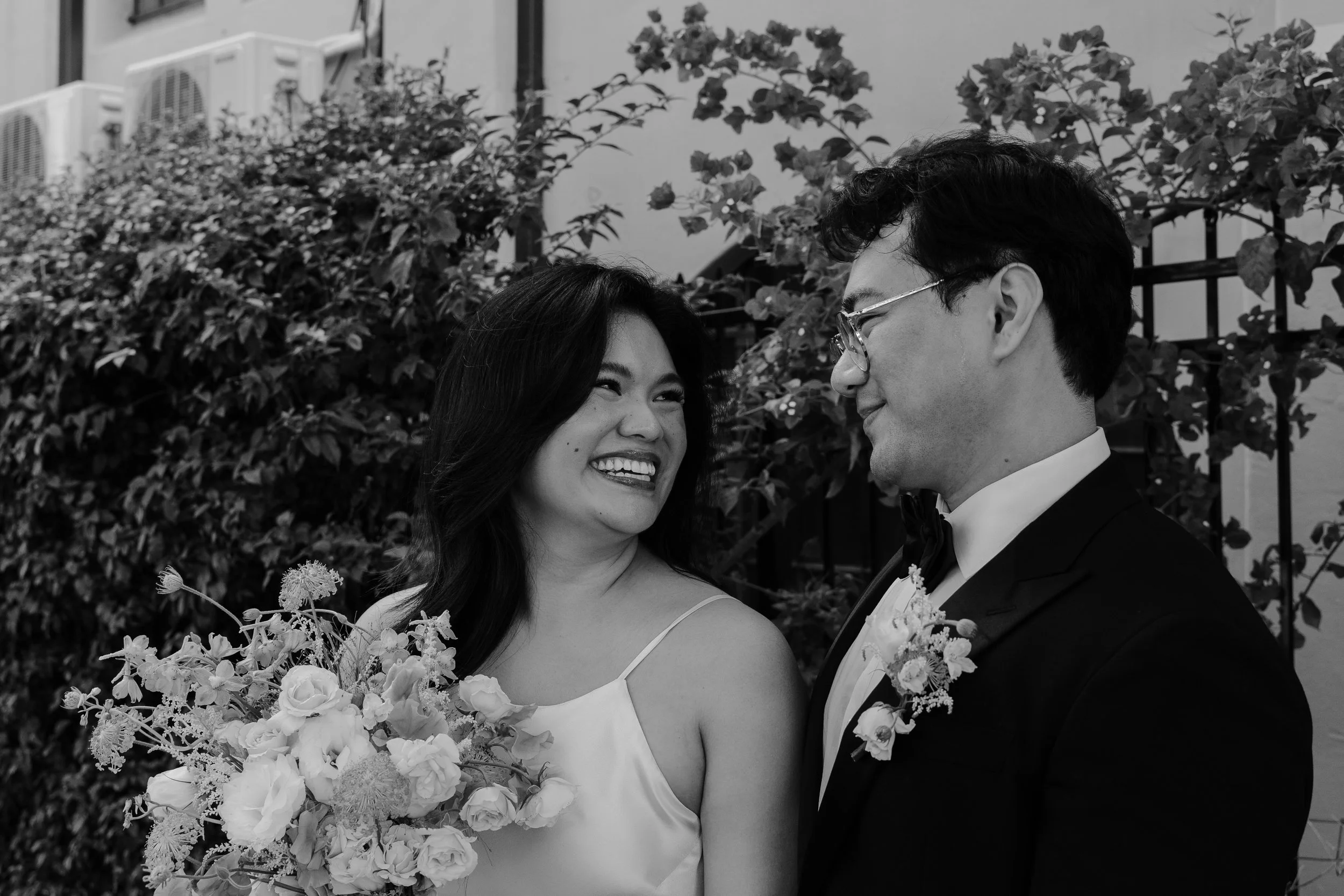 Close up of bride and groom in front of a floral-covered fence  in Old Pasadena after their Cakewalk elopement.