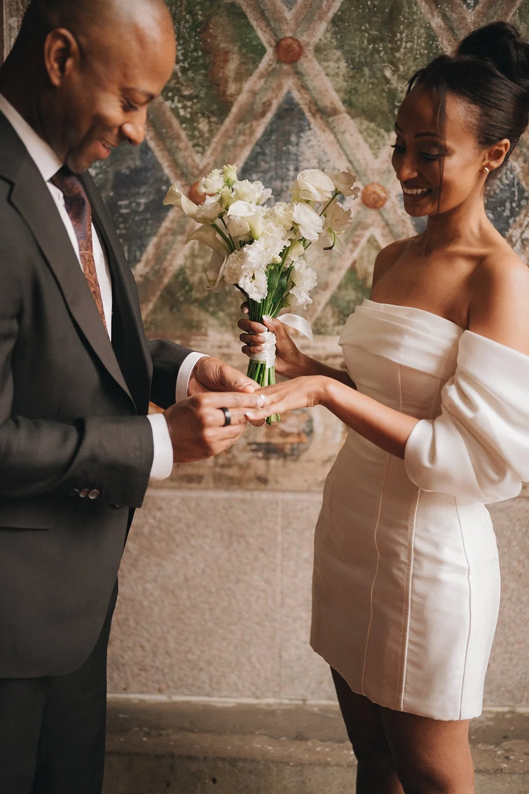 Bride and groom placing rings on each other's fingers at Bethesda Terrace during their micro wedding ceremony.