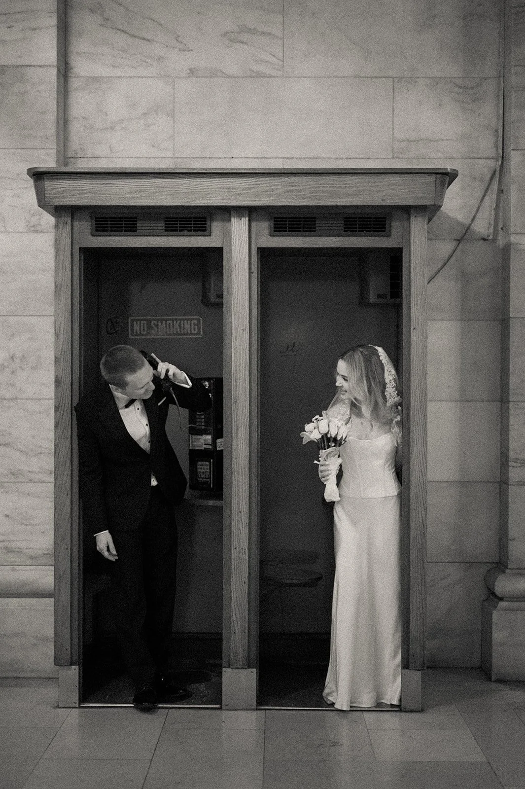 Married couple playing in the phone booth at the New York Public Library after their Cakewalk elopement.