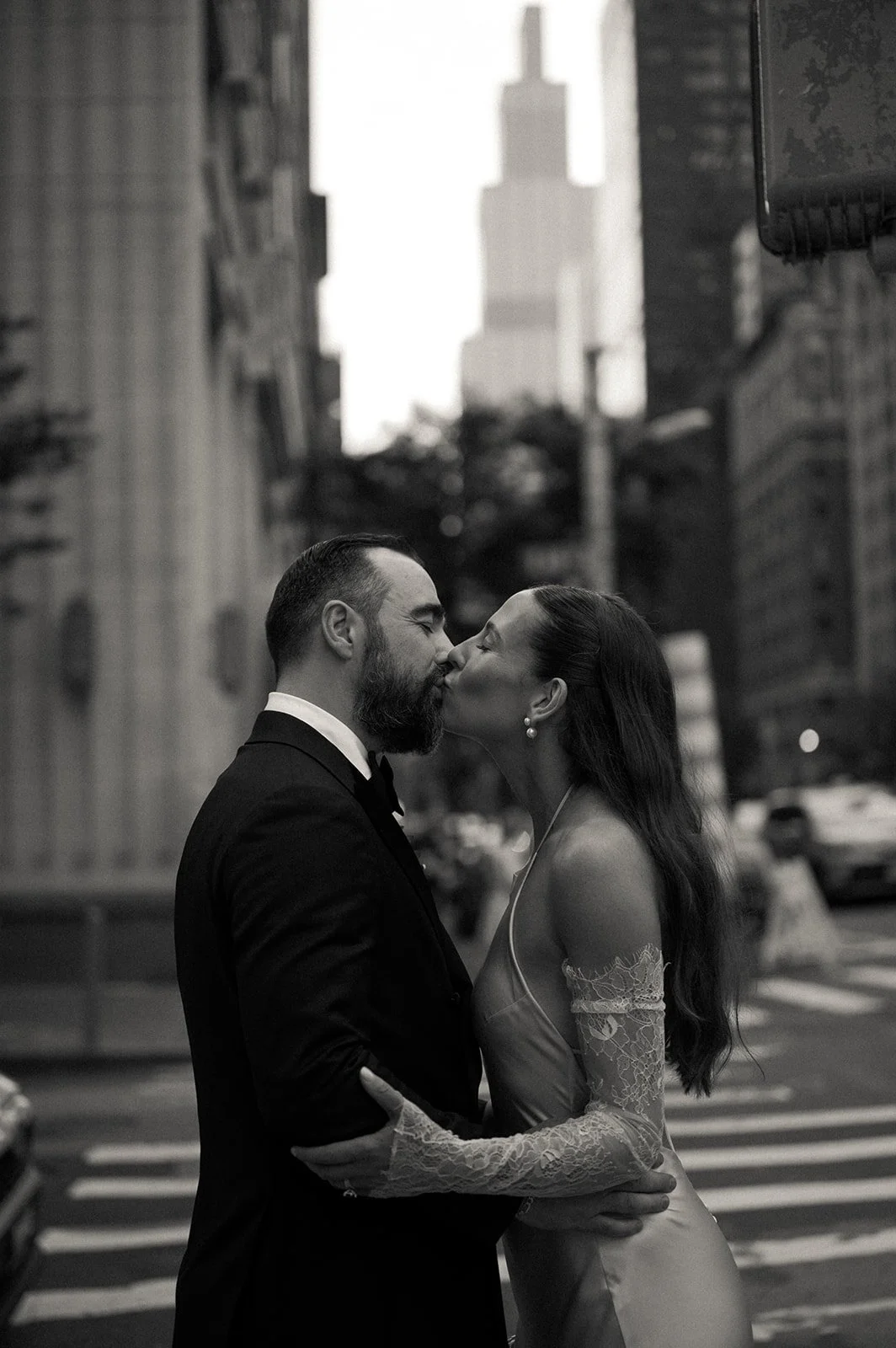 Bride and groom kissing near a crosswalk by Fifth Avenue in New York City.