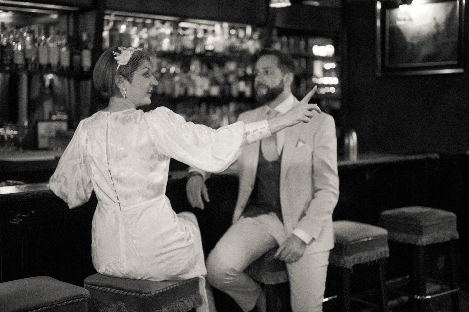 Bride and groom seated on barstools at a bar after their Cakewalk elopement.