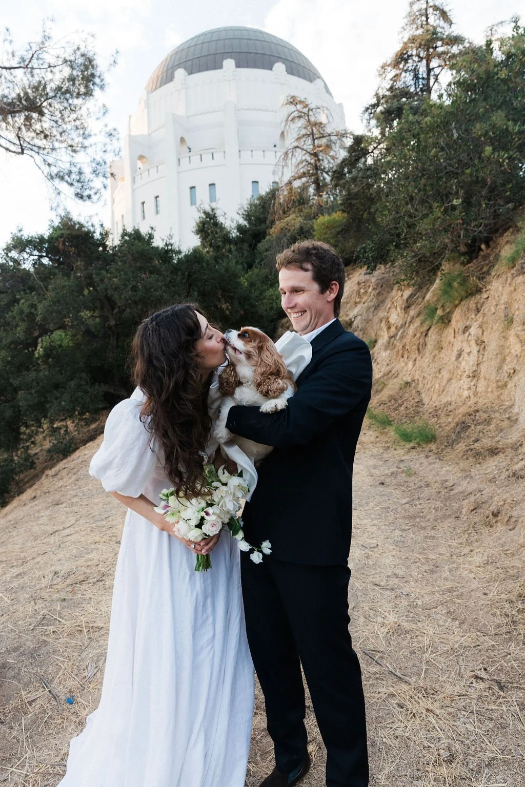 Couple kissing their dog behind Griffith Observatory at their Cakewalk elopement.