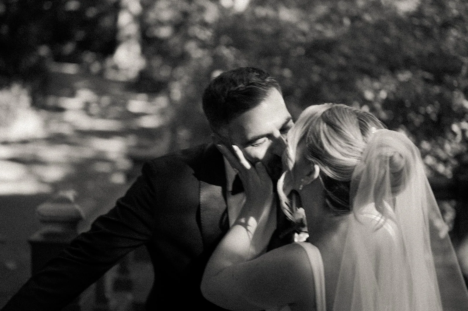 Bride and groom kissing in front the water and Bow Bridge in Central Park.