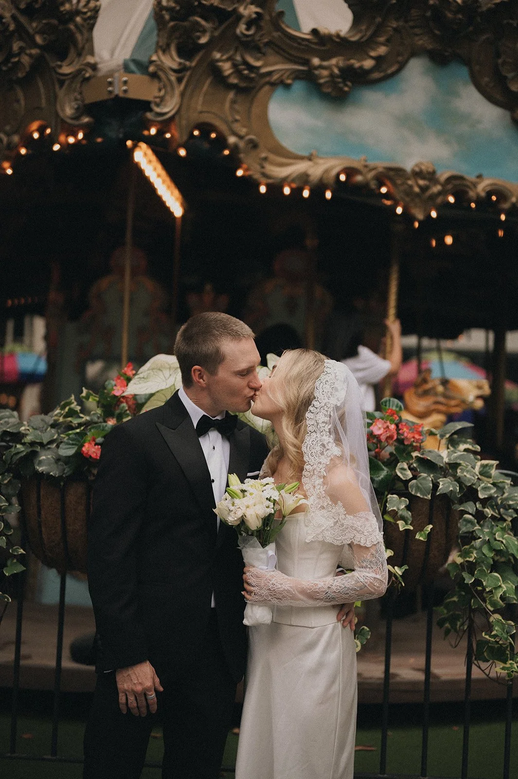 Couple kisses in front of carousel at Bryant Park before their Cakewalk elopement ceremony.