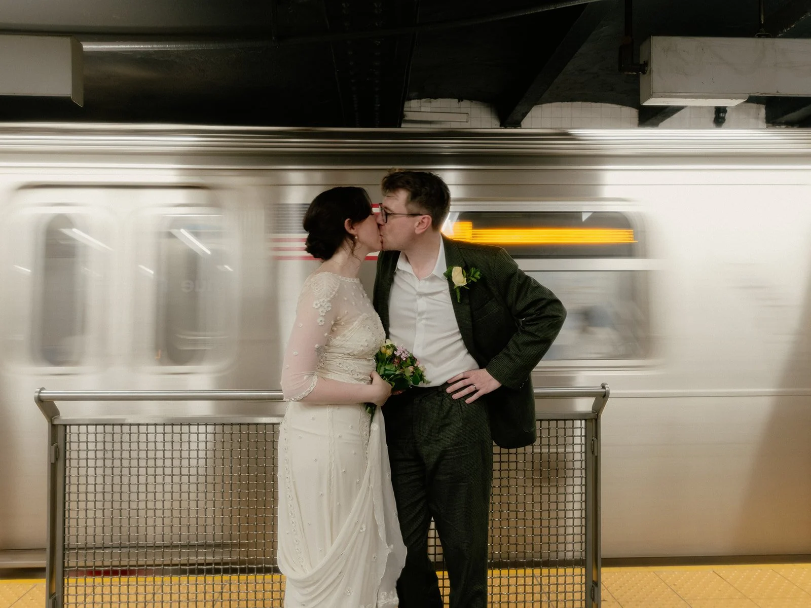 Bride and groom kissing on the subway platform in Manhattan after their Cakewalk elopement.
