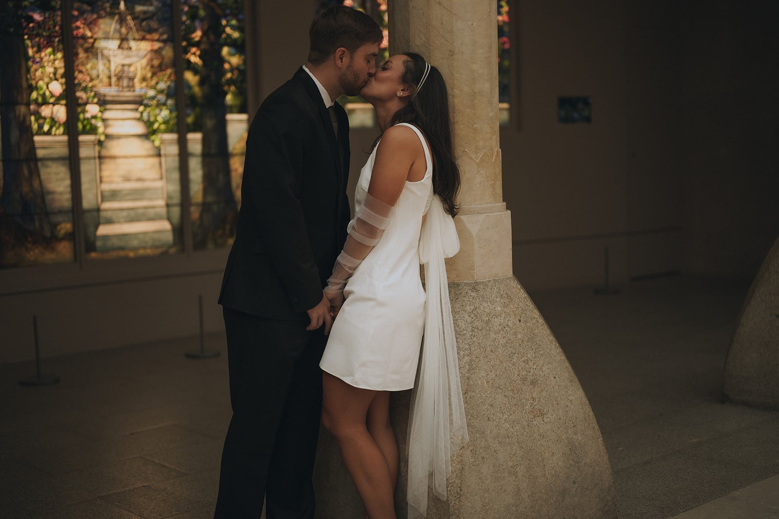 Bride and groom kissing leaned up against a column inside the Met Museum of Art after their Cakewalk elopement ceremony.