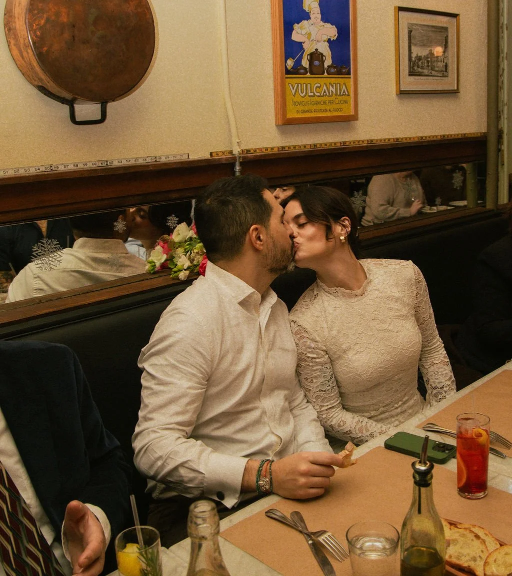 Newly married couple kissing at a dinner table after their Cakewalk elopement ceremony.