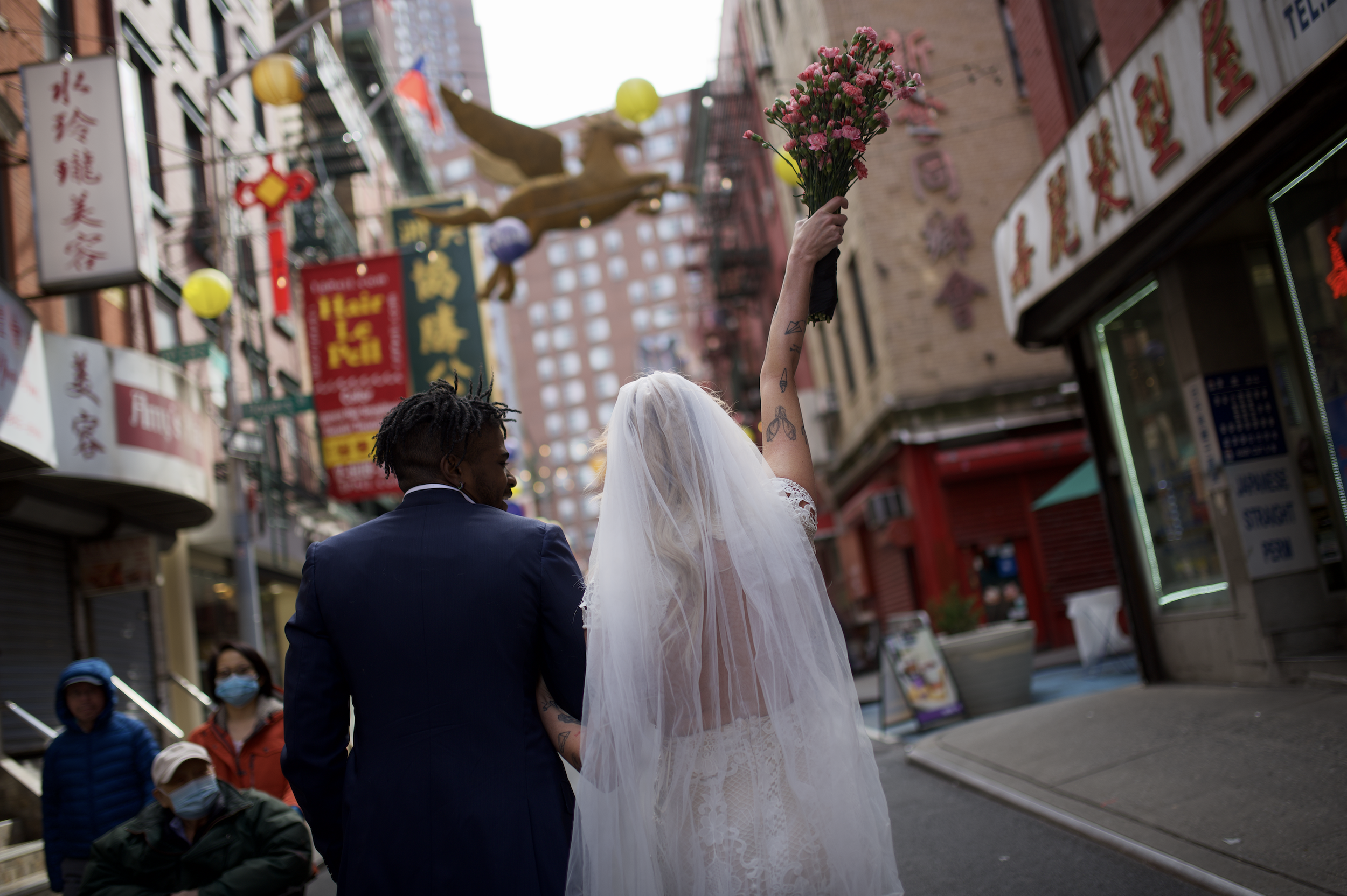 Bride and groom cheering while walking through Chinatown, lanterns overhead celebrating their Cakewalk elopement.