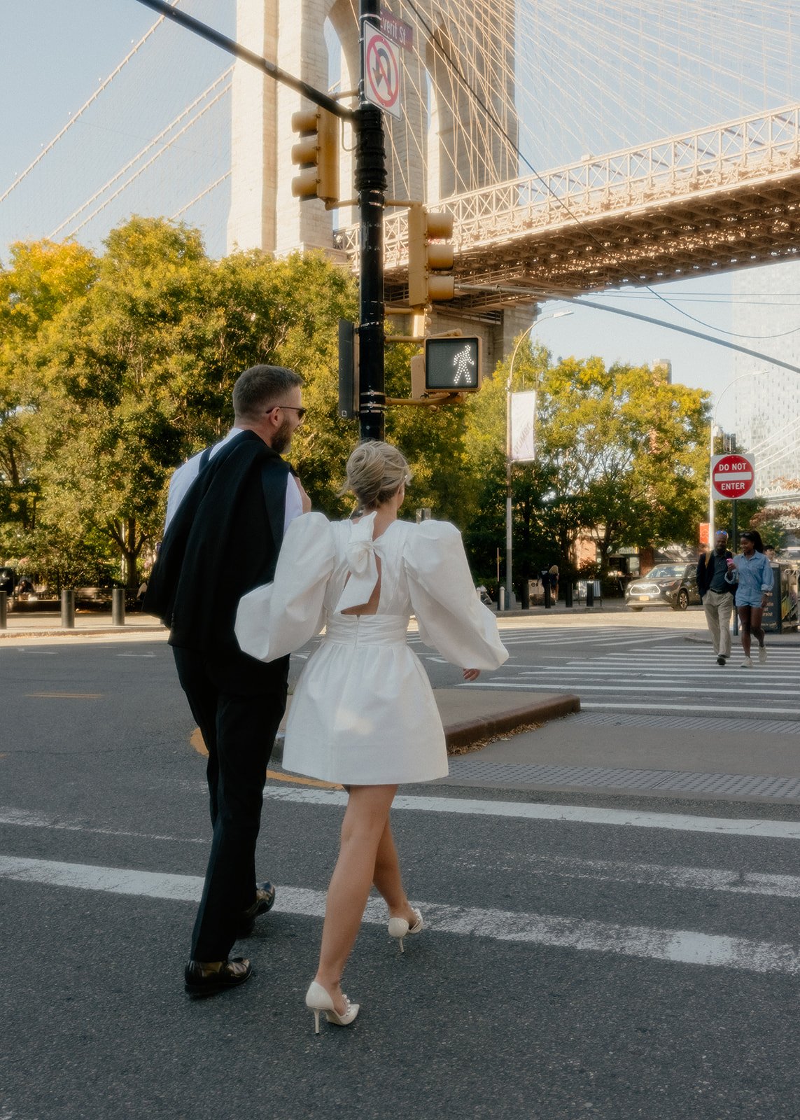 Bride and groom crossing the street, walking toward the Brooklyn Bridge after their Cakewalk elopement.
