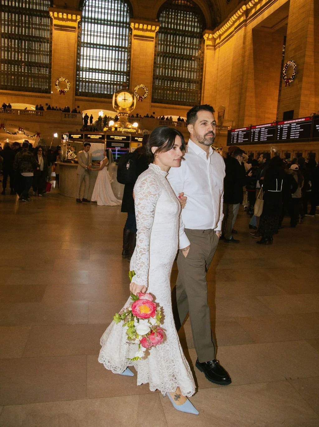Married couple with a bouquet walking through Grand Central Station after their Cakewalk elopement ceremony.