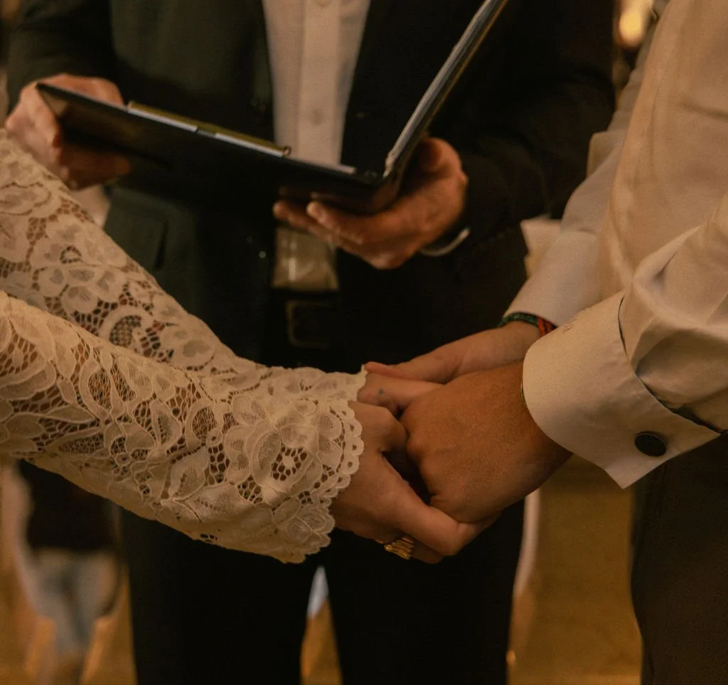 Close up of couple getting married at Grand Central Station, an officiant standing between them, holding a book.