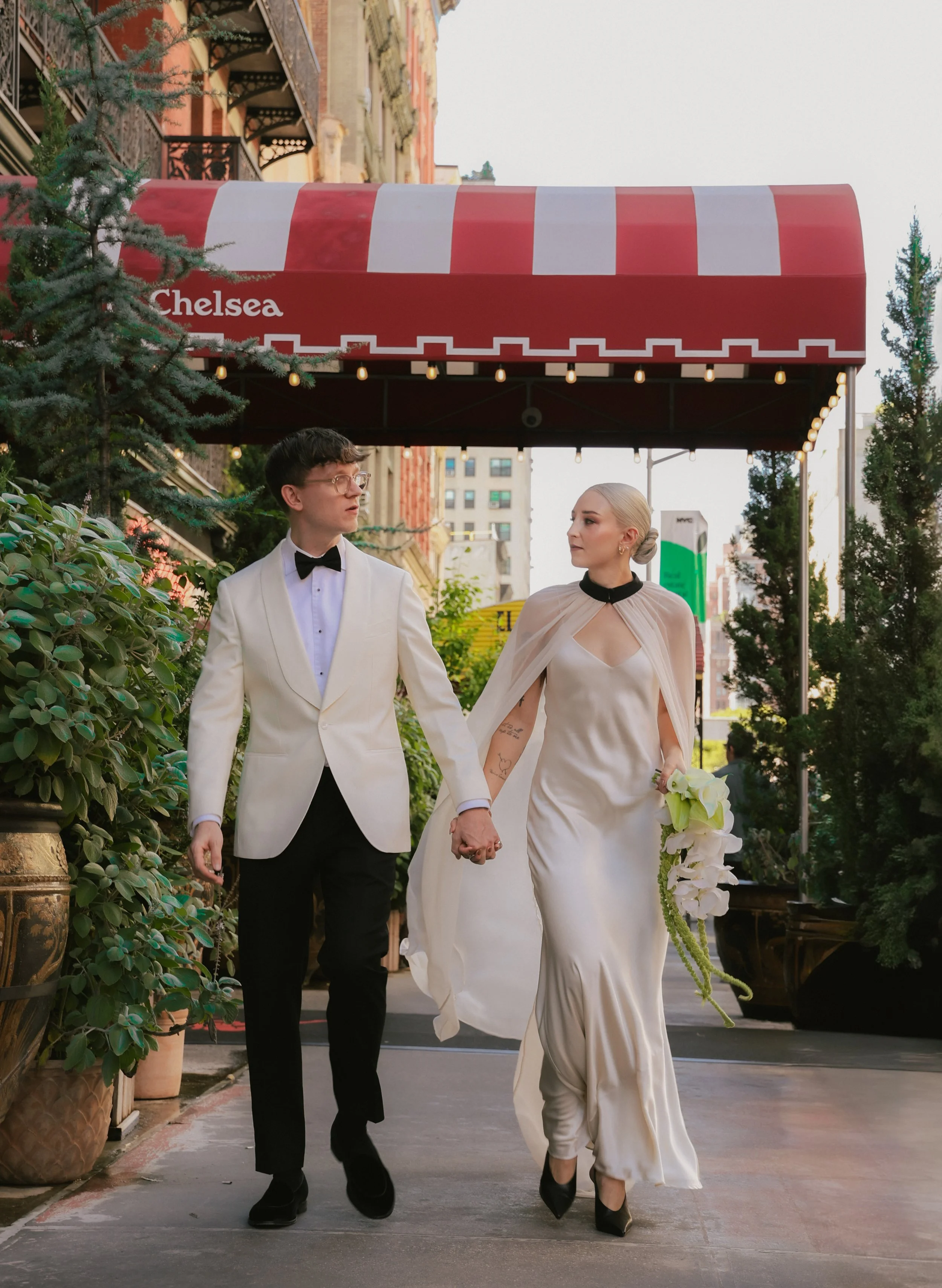Bride and groom walk down the street in front of the Hotel Chelsea in Manhattan, New York.