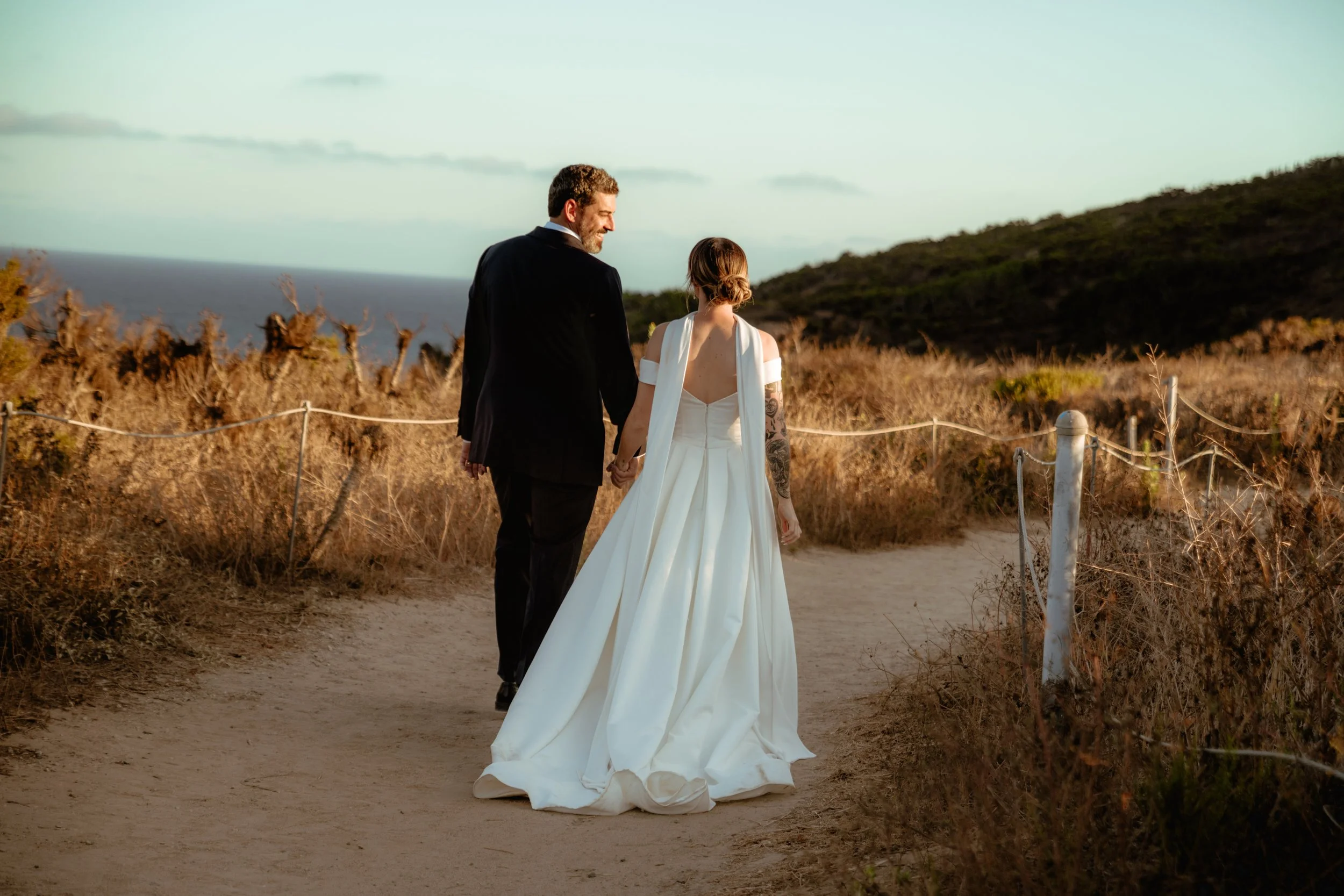 Couple walking the trails at Point Dume after their Cakewalk elopement ceremony at Zuma Beach.