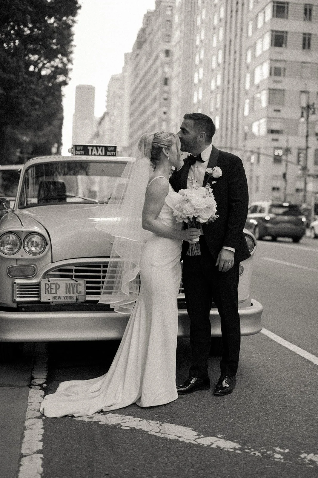 Bride and groom posing in front of a vintage, yellow checkered NYC taxi on the streets of Manhattan.