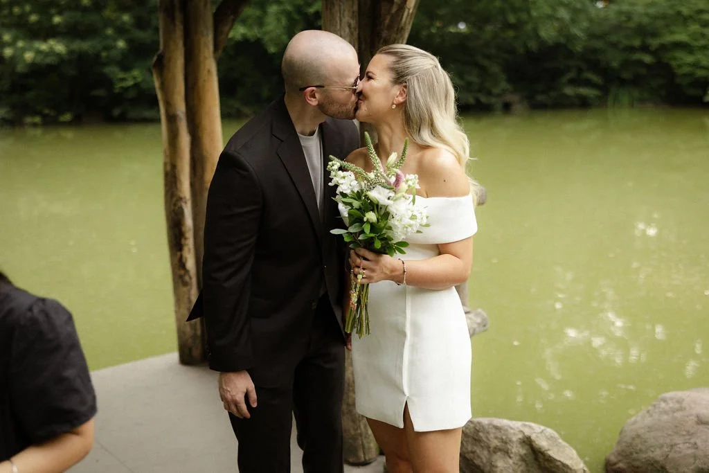 Bride and groom kissing under the wooden lakeside pavilion at Wagner Cove after their Cakewalk NYC elopement.