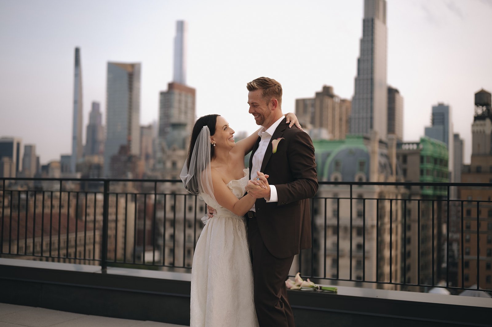 Bride and groom dancing on a Manhattan rooftop with the skyline in the background after their elopement ceremony by Cakewalk.