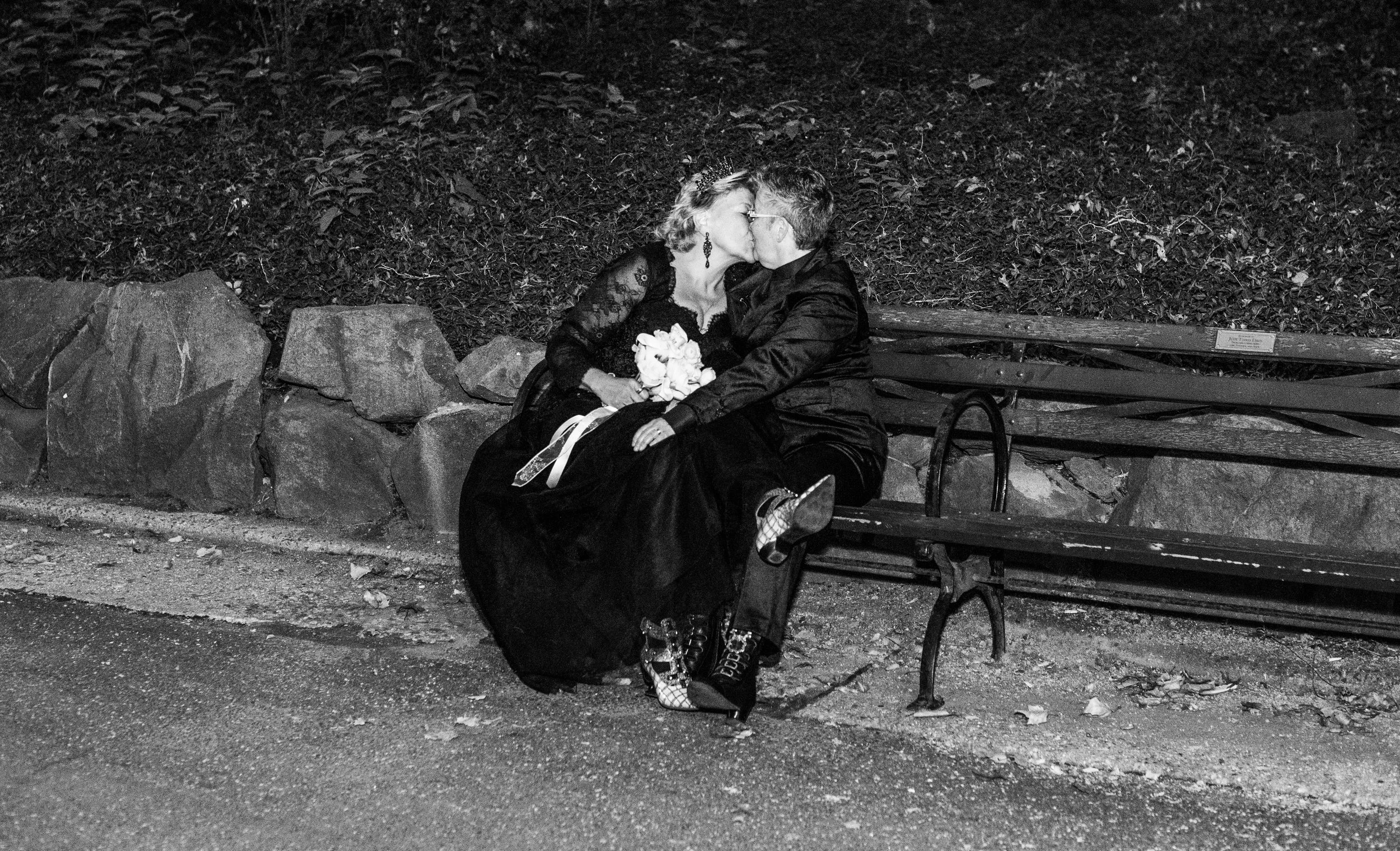 Two brides kissing on a Central Park bench after their LGBTQ-friendly Cakewalk elopement.