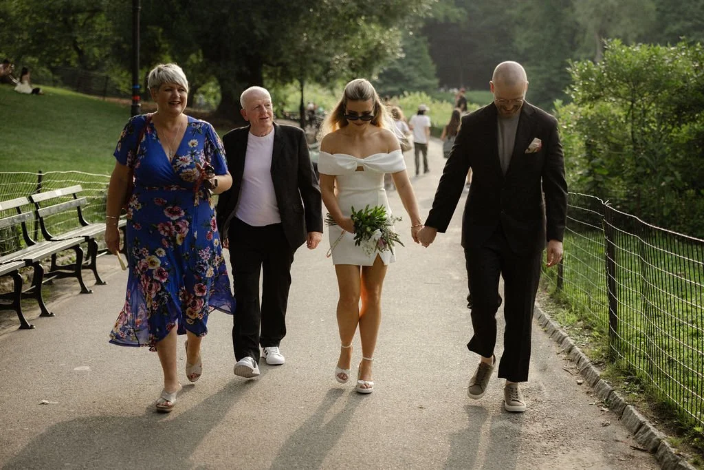 Bride and groom walking with family through Central Park after their Cakewalk elopement.